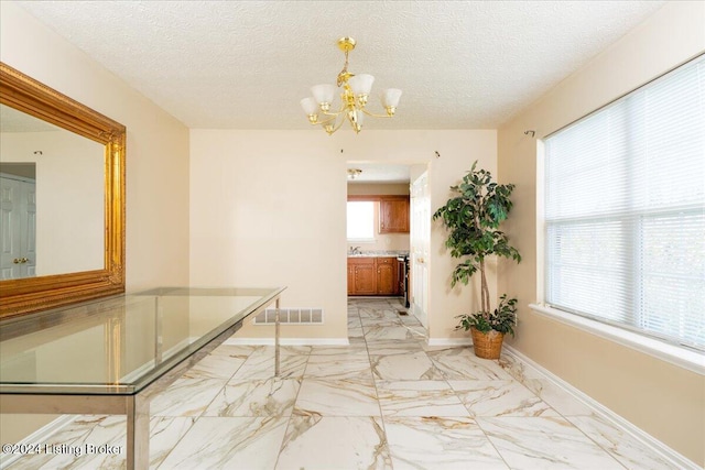 hallway featuring a textured ceiling and a notable chandelier