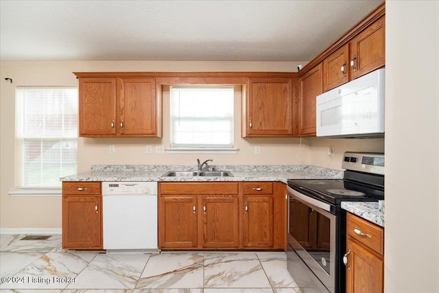 kitchen featuring a textured ceiling, light stone countertops, white appliances, and sink