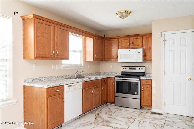 kitchen featuring a textured ceiling, light stone counters, sink, and white appliances