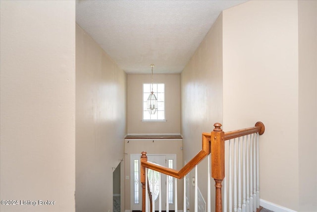 stairs with a notable chandelier and a textured ceiling