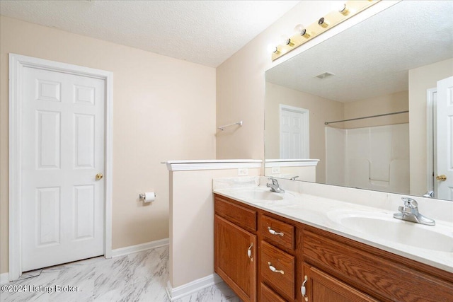 bathroom with vanity, a shower, and a textured ceiling