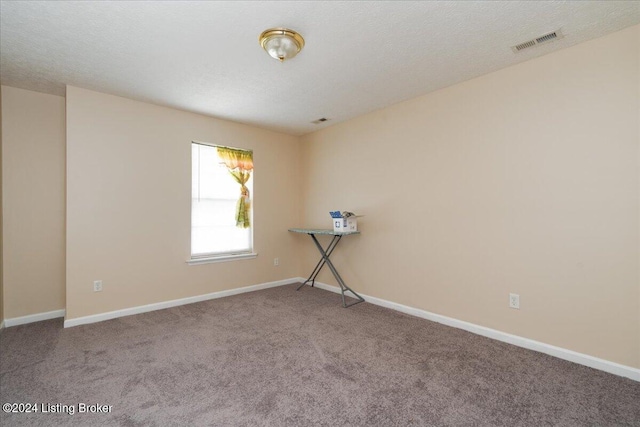 carpeted empty room with a textured ceiling