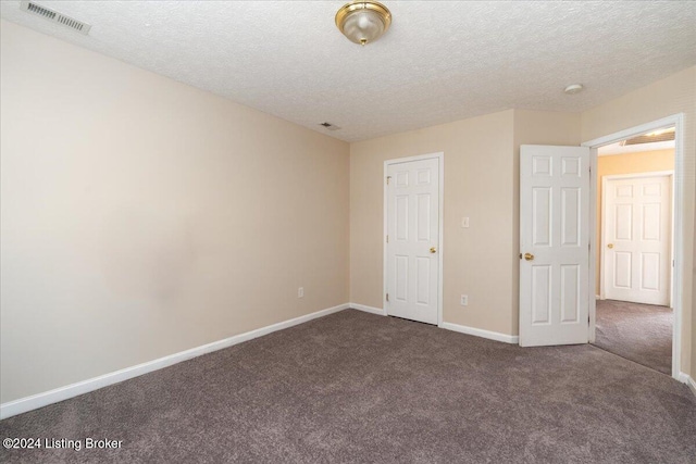 unfurnished bedroom featuring a textured ceiling and dark colored carpet