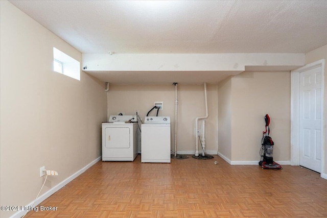 clothes washing area with light parquet floors, a textured ceiling, and washing machine and clothes dryer