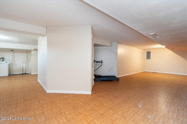 basement with washer / clothes dryer, electric panel, light parquet flooring, and a textured ceiling