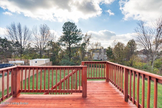 wooden deck with a lawn and a storage unit