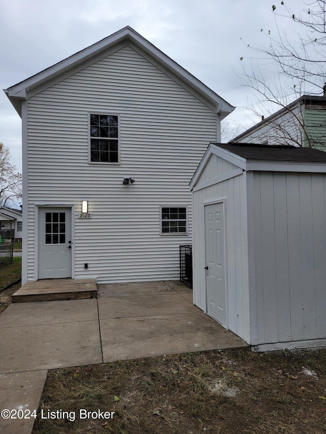 back of property with a shed and a patio