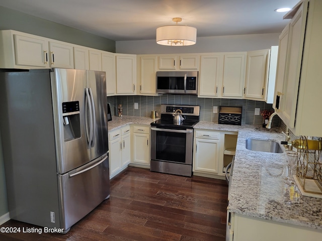 kitchen featuring dark wood-type flooring, sink, light stone countertops, appliances with stainless steel finishes, and tasteful backsplash