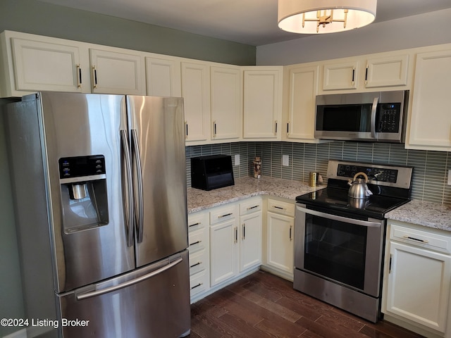 kitchen featuring light stone countertops, stainless steel appliances, white cabinets, and dark wood-type flooring