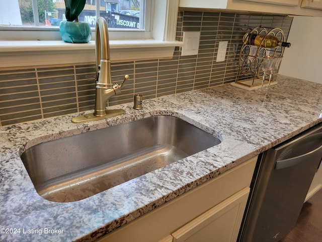 room details with backsplash, light stone countertops, sink, and stainless steel dishwasher