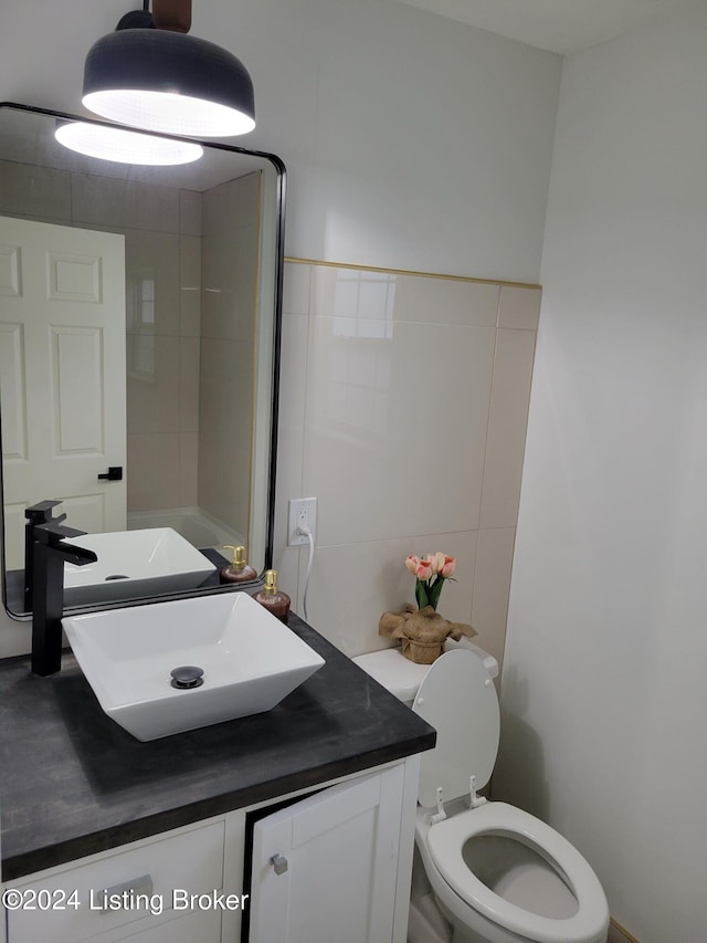 bathroom featuring vanity, toilet, and tile walls