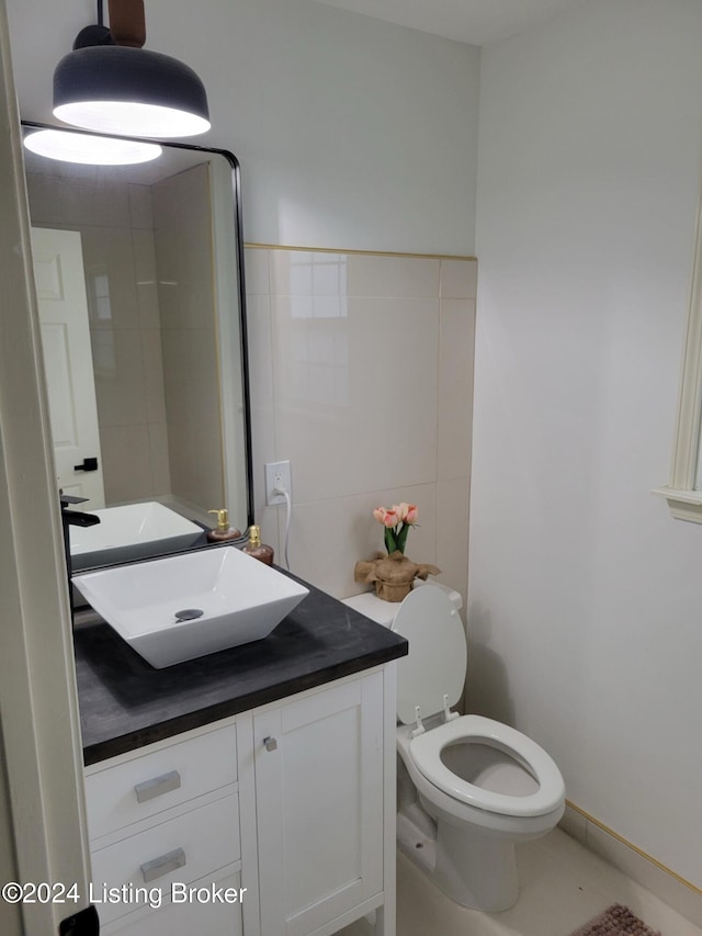 bathroom featuring vanity, toilet, and tile walls