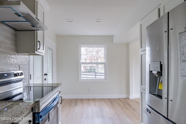 kitchen featuring ventilation hood, light hardwood / wood-style flooring, light stone countertops, tasteful backsplash, and stainless steel appliances