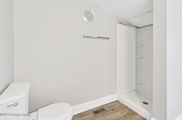 bathroom featuring toilet, a shower, and hardwood / wood-style floors