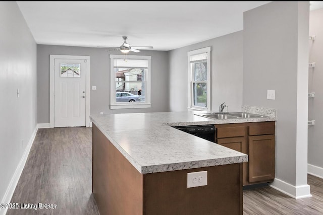 kitchen featuring kitchen peninsula, black dishwasher, wood-type flooring, and sink