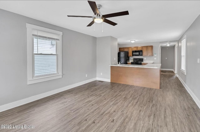 kitchen featuring black appliances, kitchen peninsula, ceiling fan, and hardwood / wood-style flooring