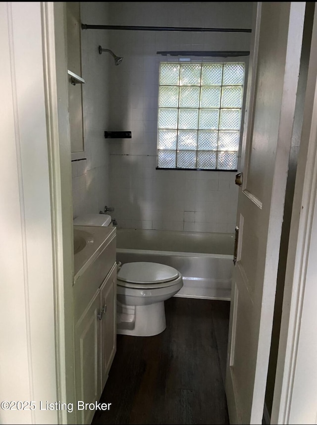 full bathroom with vanity, tiled shower / bath combo, toilet, and hardwood / wood-style flooring