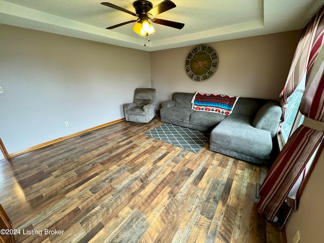 sitting room with hardwood / wood-style floors, a raised ceiling, and ceiling fan