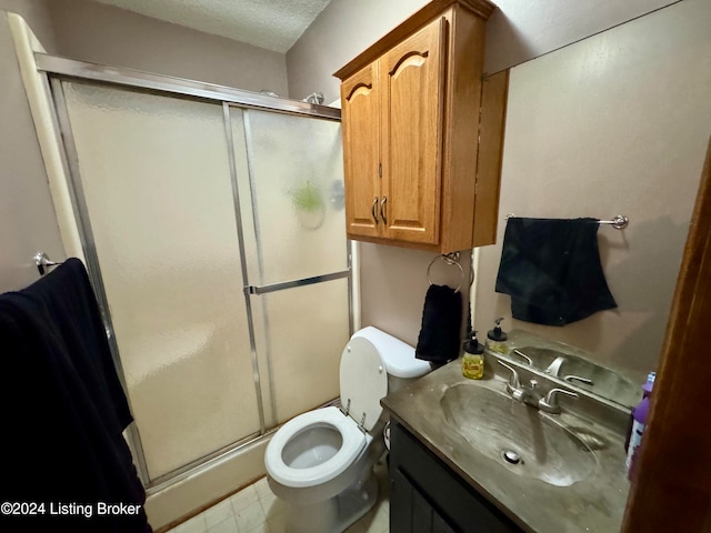 bathroom featuring a textured ceiling, vanity, toilet, and walk in shower