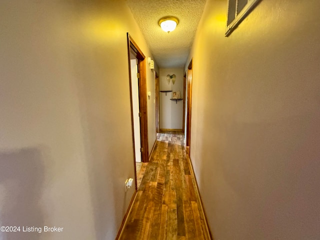 hall with dark hardwood / wood-style flooring and a textured ceiling