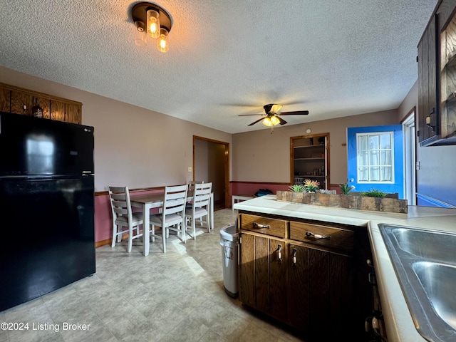 kitchen featuring a textured ceiling, black fridge, ceiling fan, and sink