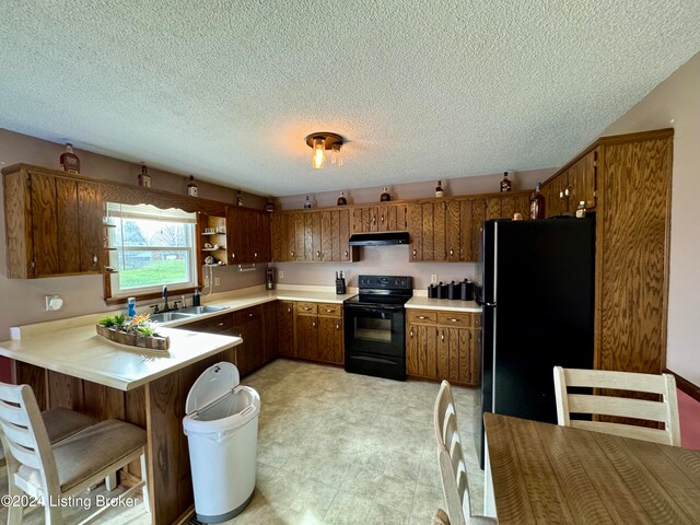 kitchen with sink, kitchen peninsula, a textured ceiling, a breakfast bar, and black appliances