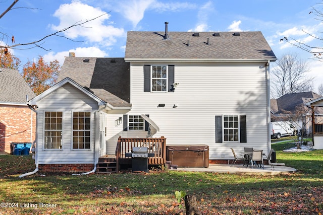 back of property featuring a patio area, a hot tub, a deck, and a lawn