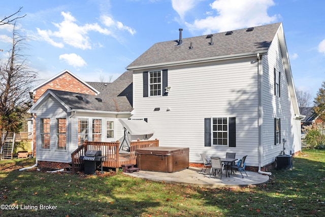 back of property with a lawn, a patio area, a wooden deck, and a hot tub