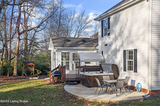 rear view of house with a patio, a hot tub, and a lawn