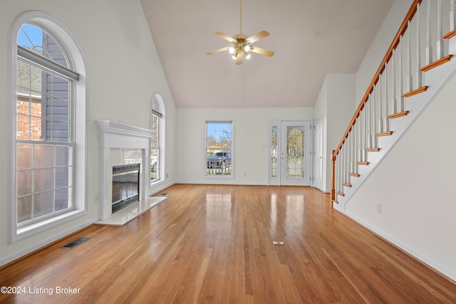 unfurnished living room with a high end fireplace, high vaulted ceiling, light hardwood / wood-style flooring, and ceiling fan