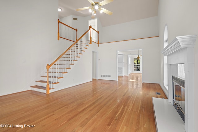 unfurnished living room with ceiling fan, light hardwood / wood-style flooring, and a high ceiling