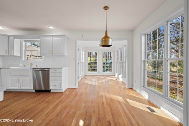 kitchen with plenty of natural light, light hardwood / wood-style flooring, stainless steel dishwasher, and sink