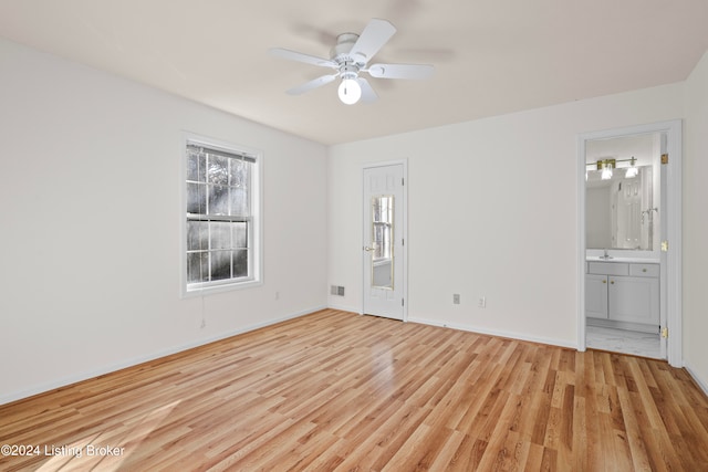 unfurnished bedroom featuring light wood-type flooring, ensuite bathroom, ceiling fan, and sink