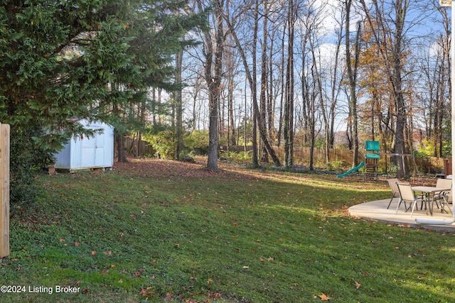 view of yard featuring a patio, a playground, and a shed