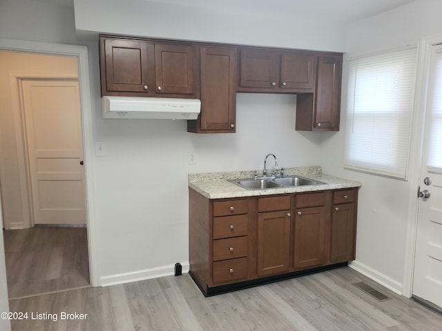 kitchen with dark brown cabinetry, sink, and light hardwood / wood-style flooring