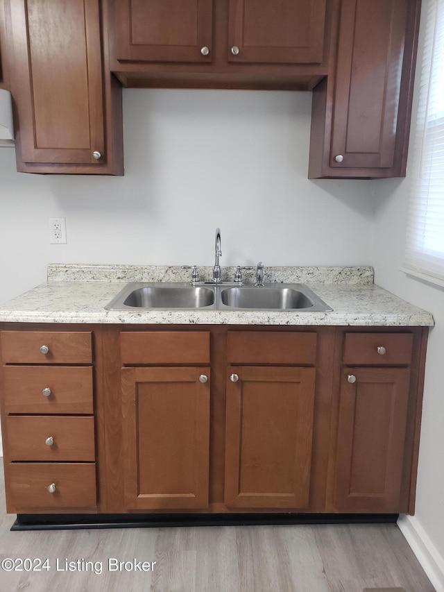 kitchen featuring light stone countertops, sink, and light hardwood / wood-style floors