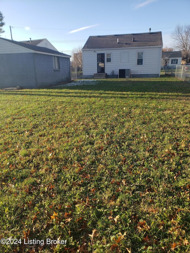 back of house with a lawn and central AC