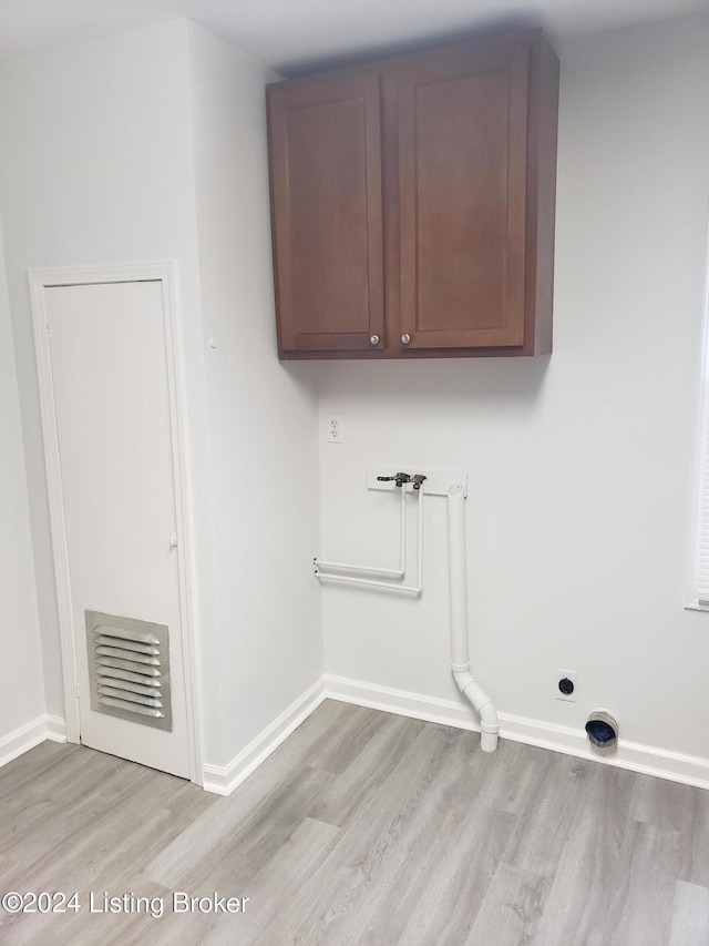 clothes washing area featuring electric dryer hookup, cabinets, washer hookup, and light wood-type flooring