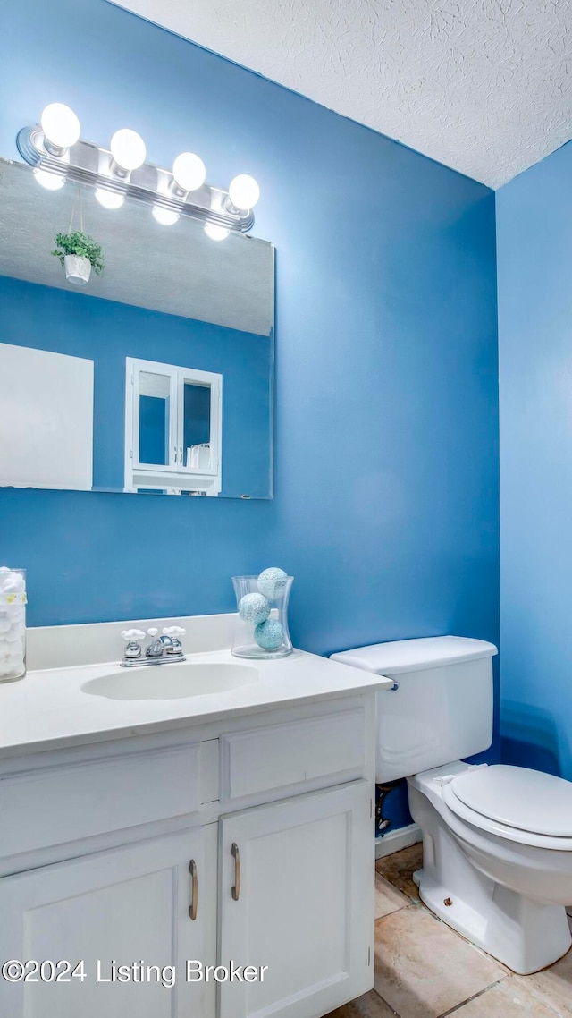 bathroom featuring tile patterned flooring, vanity, a textured ceiling, and toilet