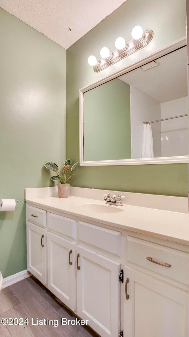 bathroom with hardwood / wood-style floors, vanity, a textured ceiling, and walk in shower