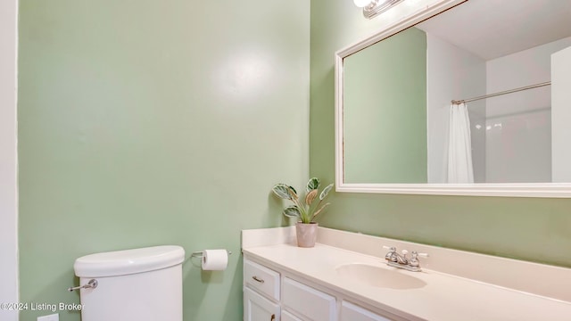 bathroom featuring a shower with shower curtain, vanity, and toilet