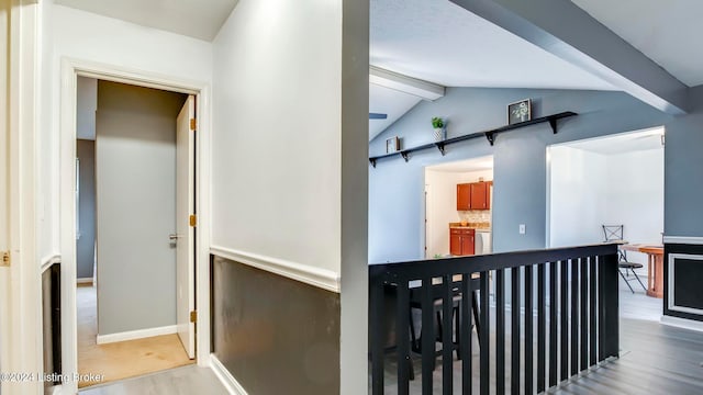 hall with hardwood / wood-style floors and vaulted ceiling with beams