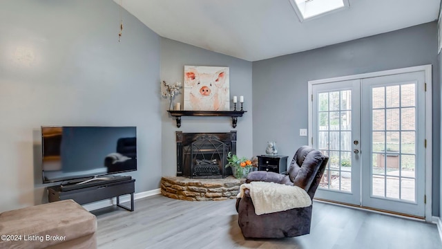 living room with vaulted ceiling, french doors, a fireplace, and light hardwood / wood-style flooring