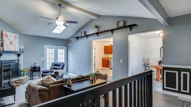 living room featuring hardwood / wood-style floors, ceiling fan, and vaulted ceiling with skylight