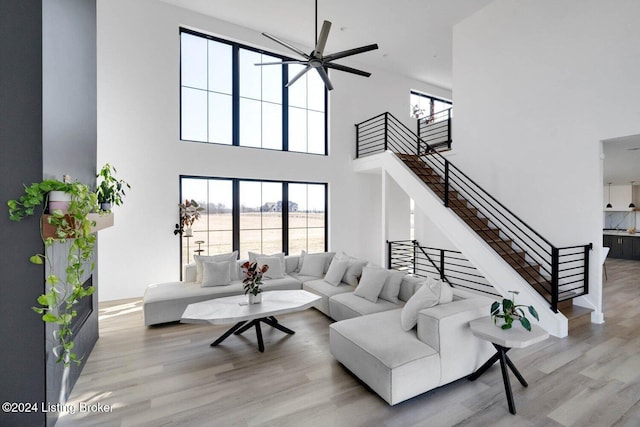 living room featuring a towering ceiling, light hardwood / wood-style floors, and ceiling fan