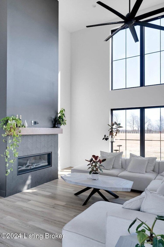 living room featuring a tile fireplace, wood-type flooring, and a towering ceiling