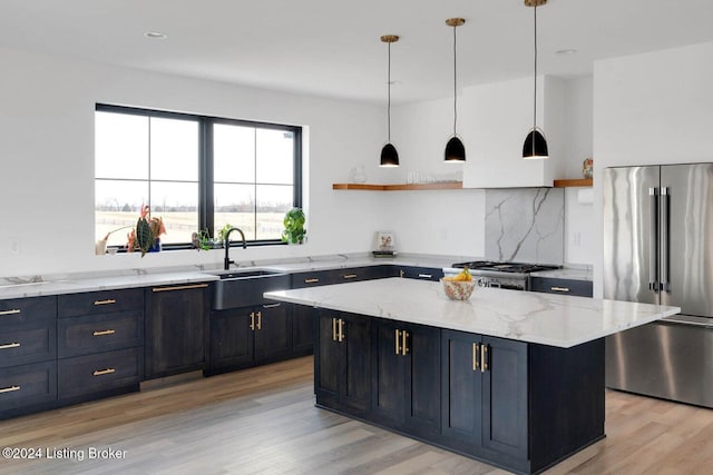 kitchen featuring sink, a center island, light stone counters, light hardwood / wood-style flooring, and appliances with stainless steel finishes