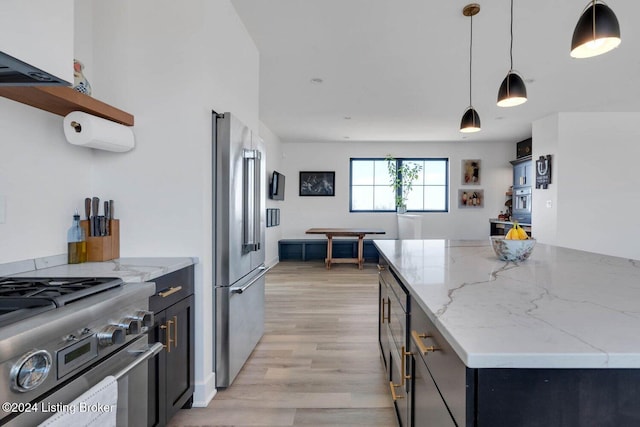 kitchen with light stone counters, pendant lighting, light hardwood / wood-style floors, high quality appliances, and a kitchen island