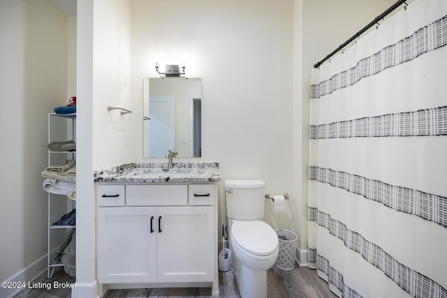 bathroom with wood-type flooring, vanity, toilet, and walk in shower