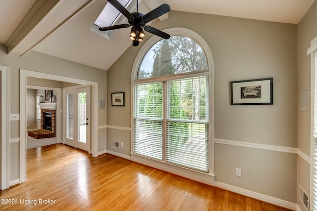 entryway with ceiling fan, light hardwood / wood-style flooring, lofted ceiling with beams, and a brick fireplace